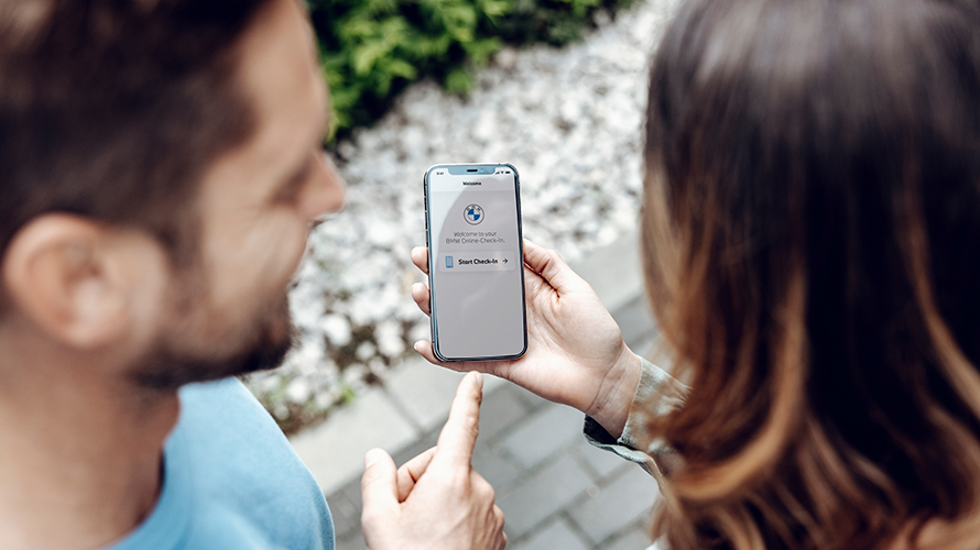 Bărbat care arată spre ecranul smartphone-ului. Logo-ul BMW este pe ecran. Bărbat care arată spre ecranul smartphone-ului. Logo-ul BMW este pe ecran.