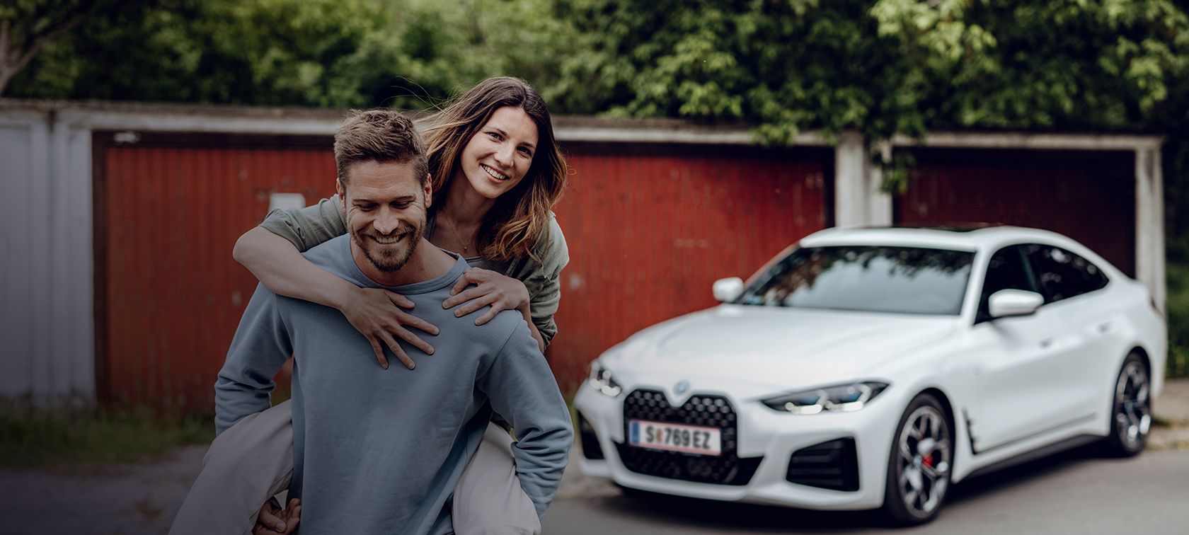 Om care zâmbeşte depărtându-se de BMW i4 şi purtând o femeie care zâmbeşte în spate. Om care zâmbeşte depărtându-se de BMW i4 şi purtând o femeie care zâmbeşte în spate.