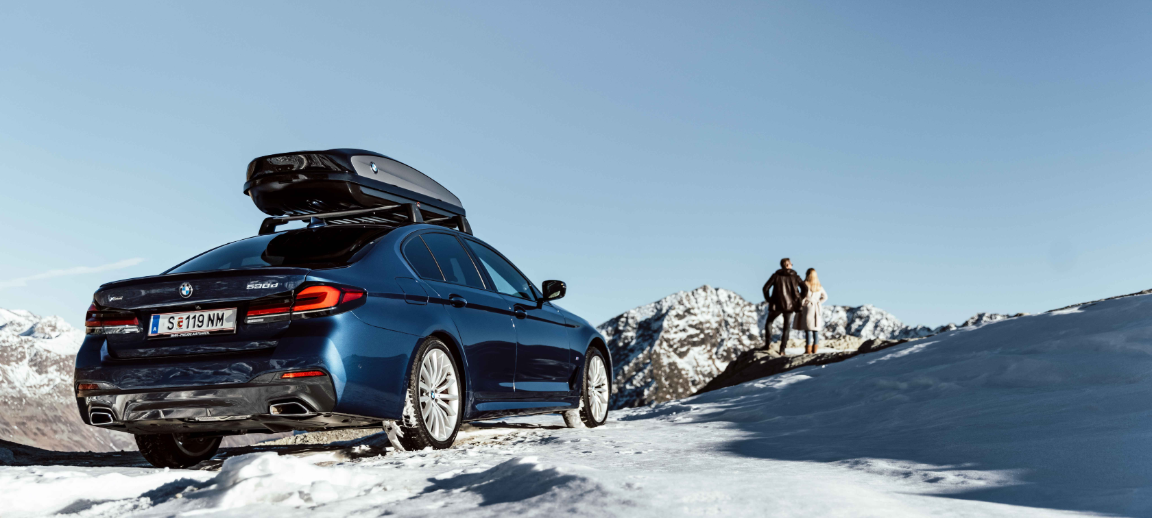 Accesorii originale BMW şi service BMW pentru toamnă şi iarnă Femeie şi bărbat râzând pe cauciucuri pentru săniuş în zăpadă